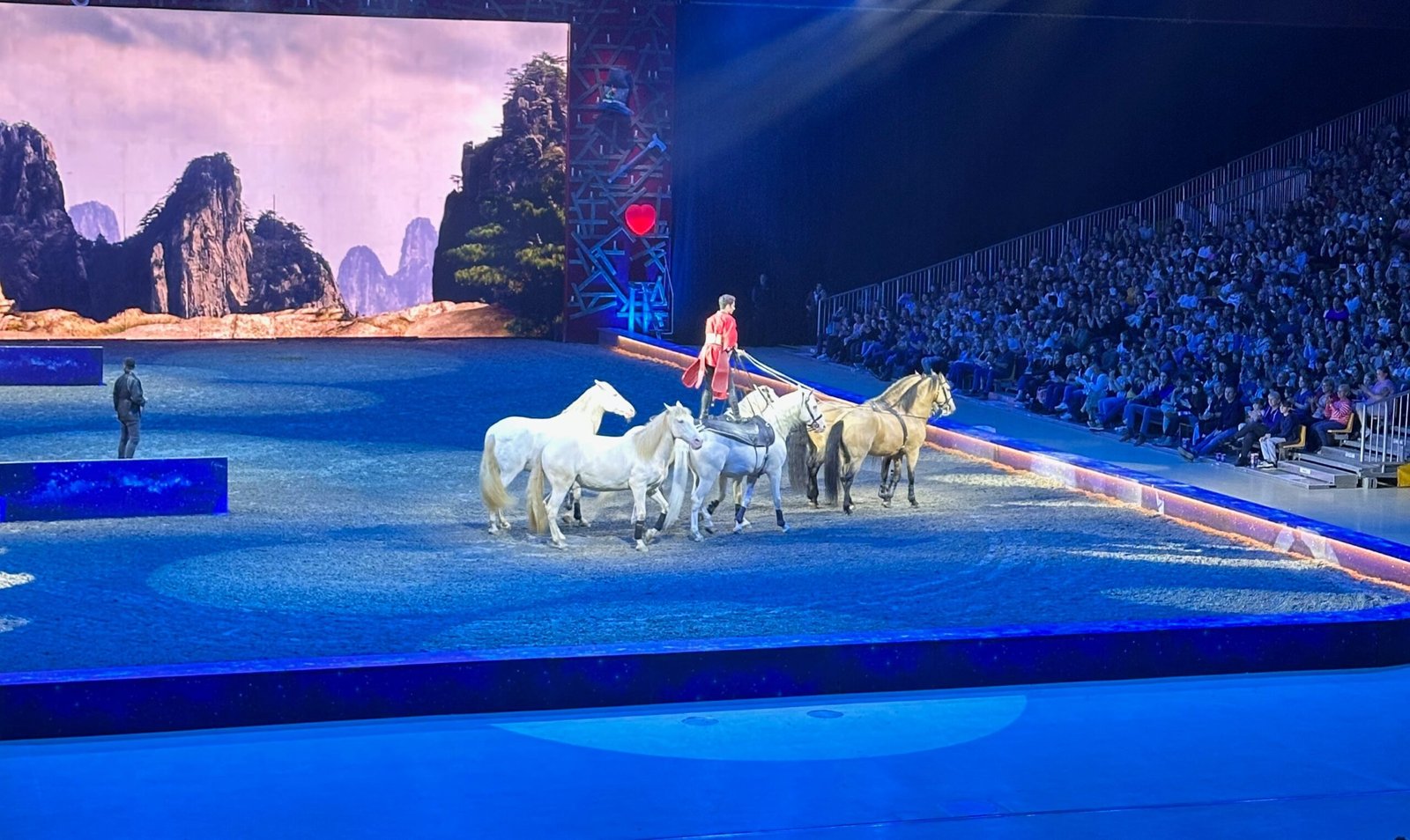 I man standing up while riding with a group of horses.